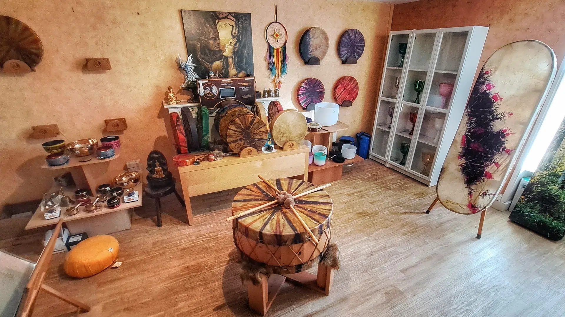 Photo de la boutique La Maison du Graal de la salle des tambours, avec tambours chamaniques, gongs, bols et graals en cristal.