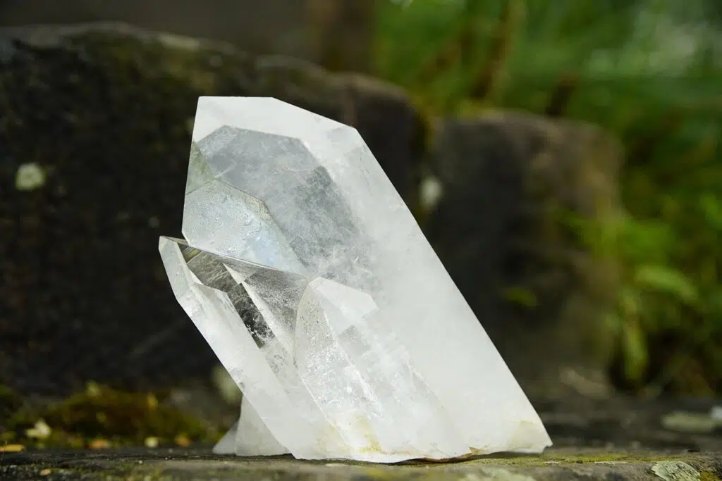 Pointe de quartz clair brute sur fond vert.